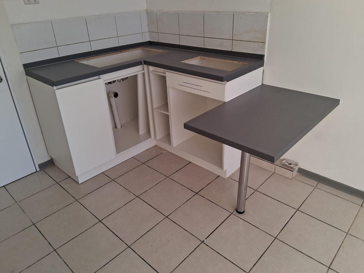 Cocina a medida con muebles blancos, cubierta oscura y mesa auxiliar abatible ya instalada