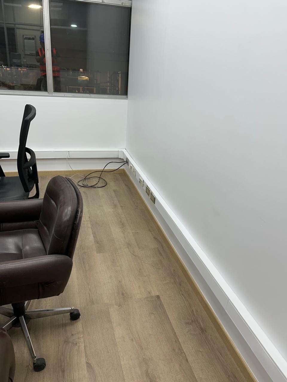 Sala con piso flotante instalado y guardapolvos blancos rematados contra el muro